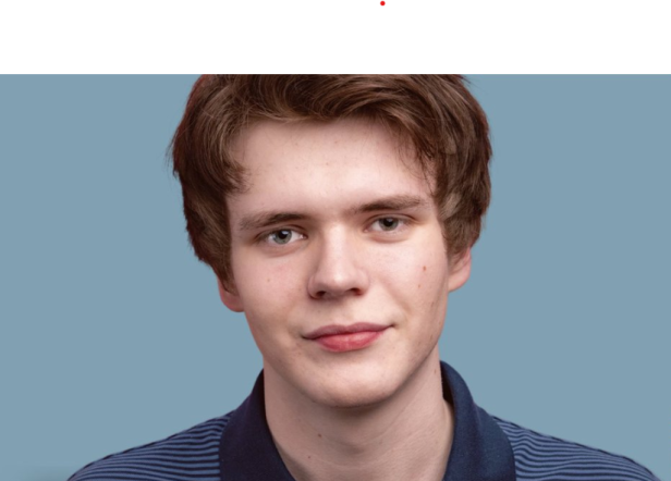 Junger Mann mit braunen Haaren vor blauem Hintergrund.