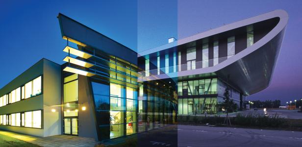 Zwei moderne Gebäude mit großen Glasfassaden und markanten architektonischen Formen bei Dämmerung.