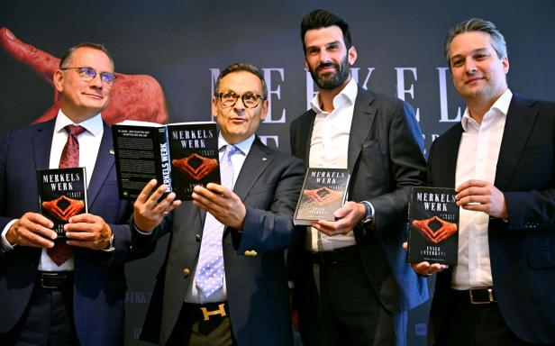 Vier Männer im Anzug präsentieren das Buch "Merkels Werk" vor dunklem Hintergrund.