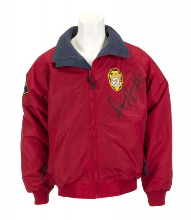 Eine rote Jacke mit Reißverschluss, einem Abzeichen und einer Unterschrift auf der Vorderseite.