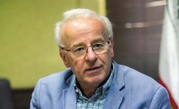 Ein älterer Mann mit weißem Haar, Brille und blauem Sakko sitzt in einem Raum und schaut nach vorn.