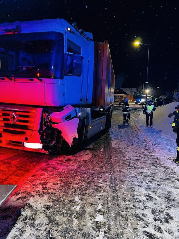 Ein beschädigter Lkw steht auf verschneiter Straße, mehrere Einsatzkräfte sind vor Ort.