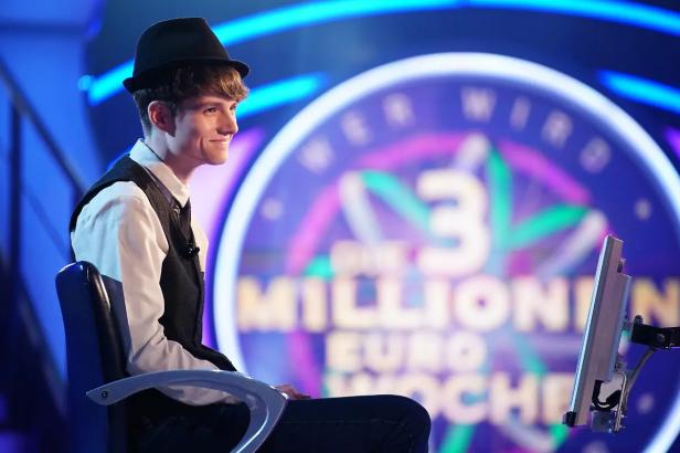 Junger Mann mit Hut und Weste sitzt auf dem Quizstuhl bei "Wer wird Millionär?".