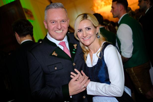 Ein lächelndes Paar in traditioneller Tracht steht eng beieinander auf einer festlichen Veranstaltung.