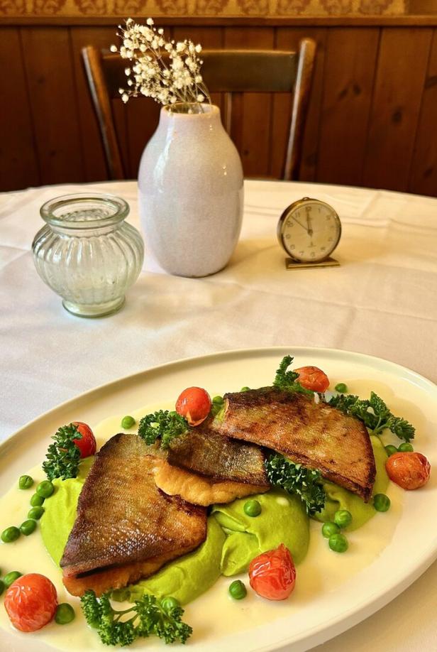 Saibling mit Erbsenpüree serviert auf einem weißen Teller. 