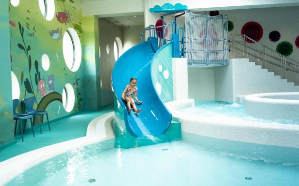 Ein Kind rutscht fröhlich die Rutsche in einem Wasserpark hinunter.