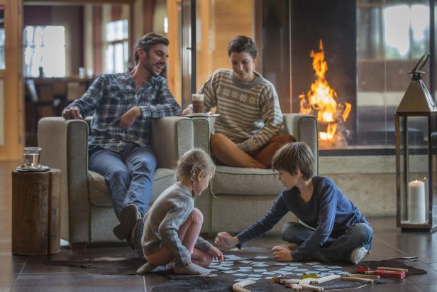 Familie entspannt gemeinsam am Kamin und spielt ein Spiel auf dem Boden.