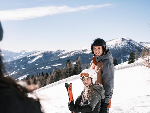 Eine Familie in Ski-Klamotten genießt die Aussicht auf die schneebedeckten Berge.