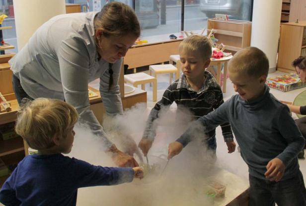 Eine Erzieherin experimentiert mit drei Kindern mit Trockeneis in einem Kindergarten.