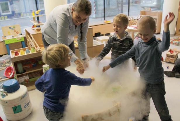 Eine Erzieherin experimentiert mit Kindern und Trockeneis in einem Kindergarten.