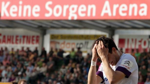 Ein frustrierter Fußballspieler hält sich den Kopf vor der „Keine Sorgen Arena“.