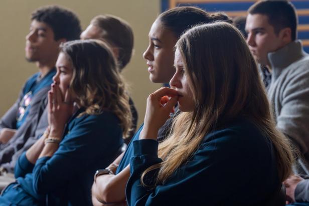 Mehrere junge Menschen sitzen nebeneinander und wirken nachdenklich oder besorgt.