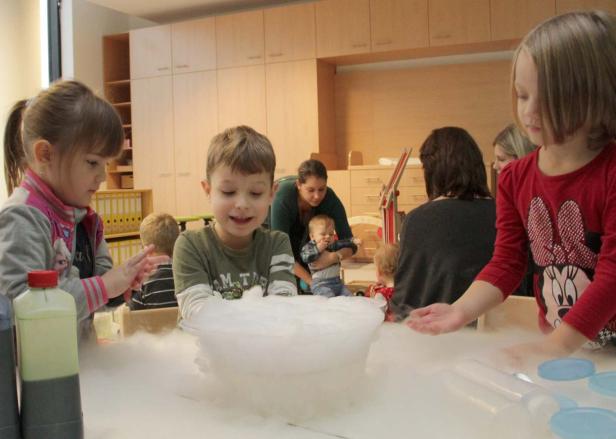 Kinder experimentieren mit Trockeneis in einem Raum.