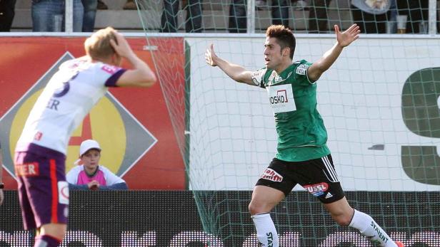 Ein Fußballspieler jubelt mit erhobenen Armen, während ein anderer den Kopf senkt.