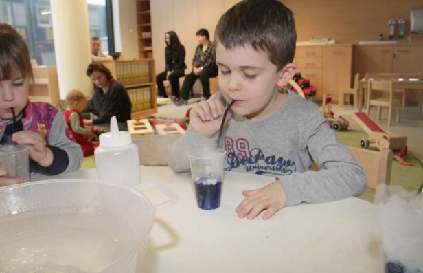 Ein Junge trinkt mit einem Strohhalm aus einem blauen Getränk, aus dem Dampf aufsteigt.