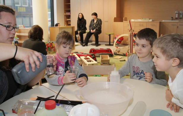 Kinder experimentieren mit Wasser und Farben in einem hellen Raum.