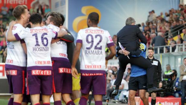 Ein Trainer wird von einem Spieler auf den Schultern getragen, während andere Spieler jubeln.