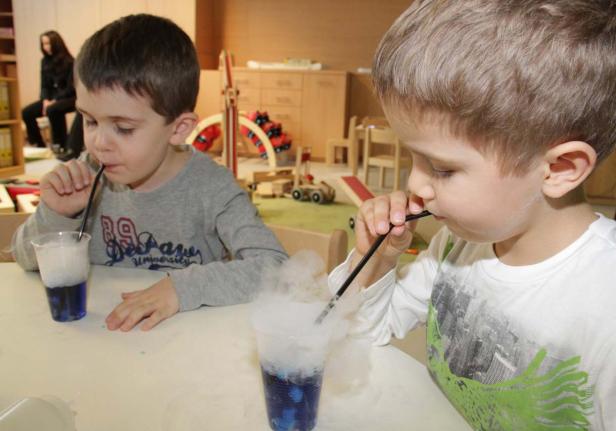 Zwei Jungen trinken blaue Getränke mit Trockeneis durch Strohhalme.