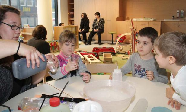 Kinder experimentieren mit Wasser und Farben in einem hellen Raum.