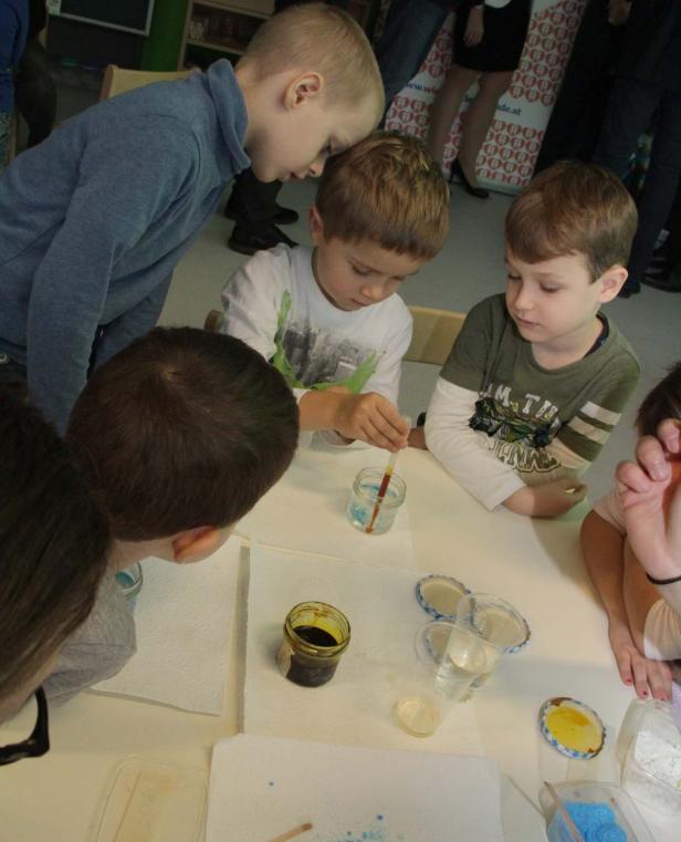 Eine Gruppe Kinder experimentiert mit Pipetten und farbigen Flüssigkeiten.