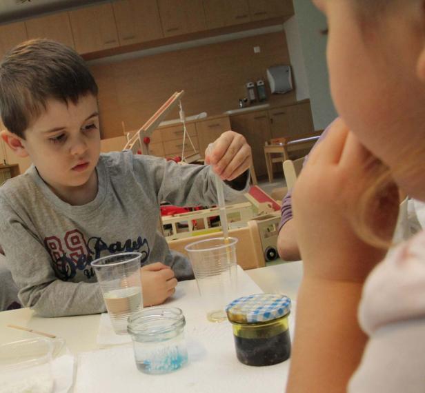 Ein Junge experimentiert mit einer Pipette und verschiedenen Flüssigkeiten.