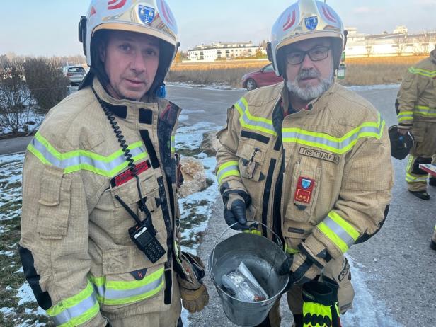 Zwei Feuerwehrmänner mit einem Kübel in der der Hand