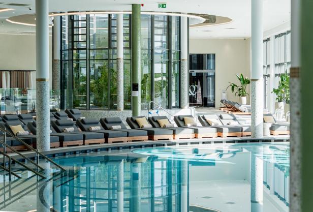 Ein Indoor-Pool mit ganz vielen Liegen drum herum 