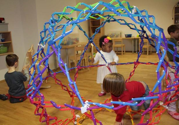 Kinder spielen mit einem großen, bunten Konstruktionsspielzeug in einem Raum.