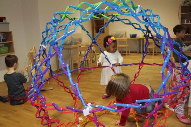 Kinder spielen mit einer großen, bunten Konstruktion im Kindergarten.