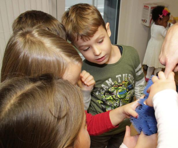 Eine Gruppe Kinder spielt mit einem blauen Konstruktionsspielzeug.