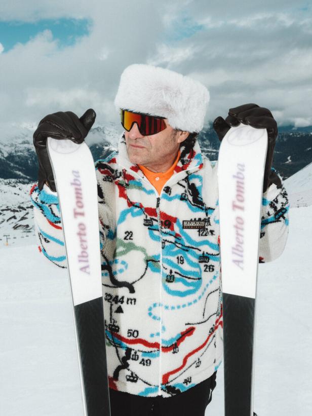 Alberto Tomba in einem bunten Fleece von Napapijiri steht mit seinen Skiern im Schnee