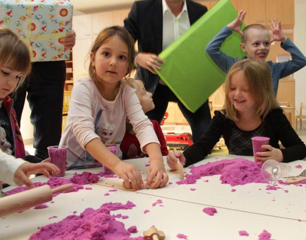 Eine Gruppe Kinder spielt mit lila kinetischem Sand an einem Tisch.