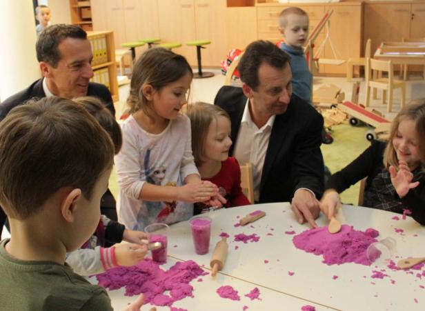 Kinder und zwei Männer spielen mit lila Knete an einem Tisch.