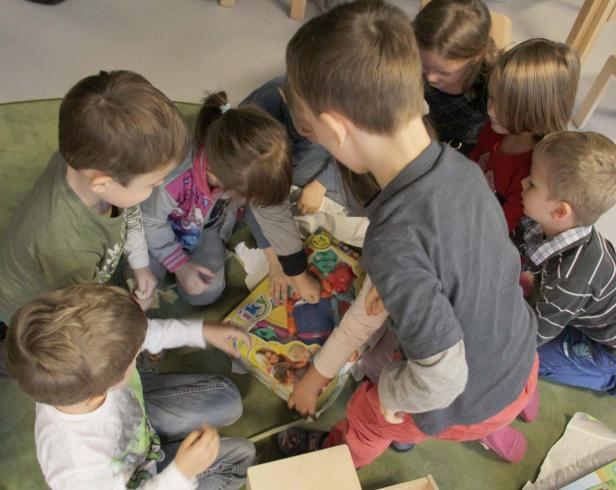 Eine Gruppe Kinder sitzt auf dem Boden und spielt mit einem Spielzeug.