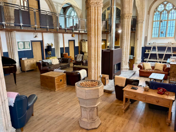 Großzügiges Wohnzimmer mit Sofas, Kamin und historischen Säulen in umgebauter Kirche.