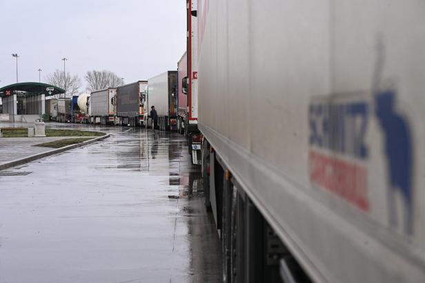 Auf regennasser Fläche stehen mehrere Lastwagen in einer Reihe.