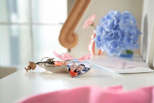 Ein herzförmiger Schlüsselanhänger mit einem Paarfoto drauf, auf einer Anrichte 