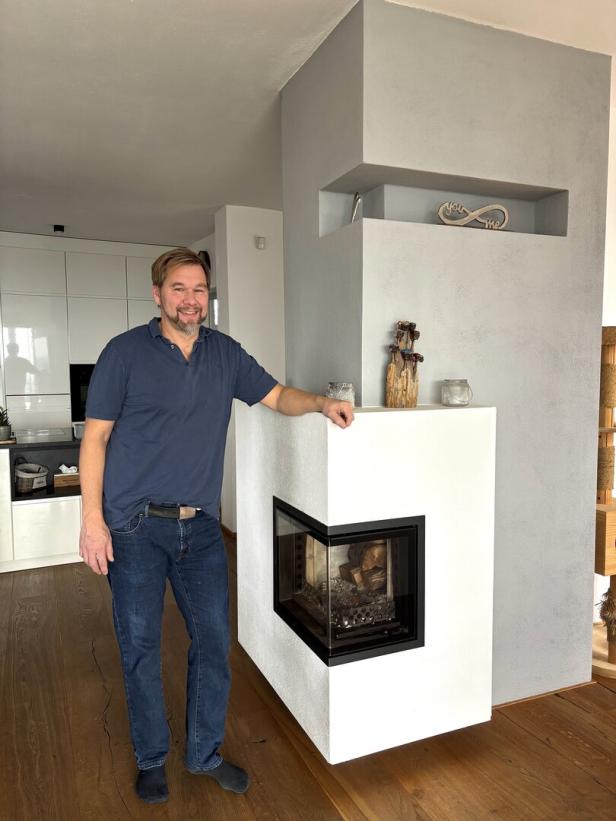 Hafner Wolfgang Thumberger steht neben einem Kachelofen