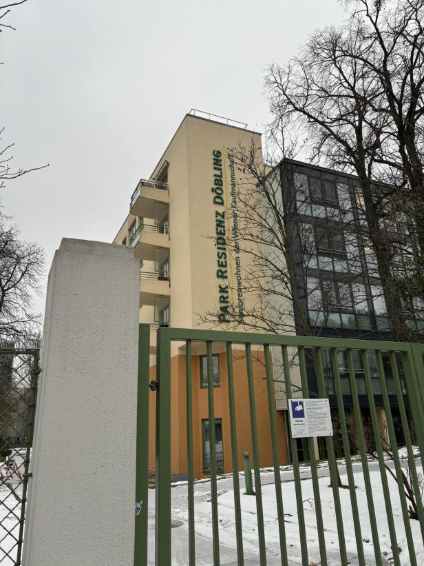 Grüner Zaun vor einem gelben Gebäude