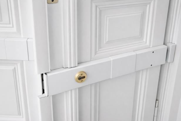 Ein Balkenschloss an einer weißen Holztür 