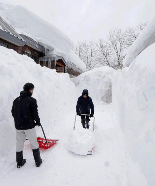 People remove snow near a house in Aomori, northeastern Japan, as heavy snow continues to hit the region