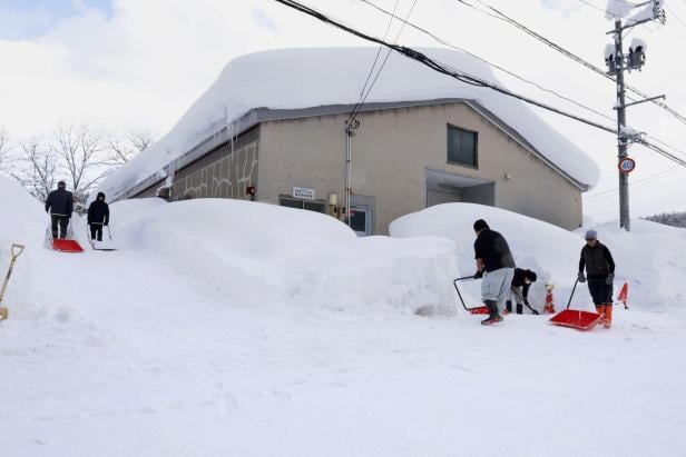 People remove snow near a house in Aomori, northeastern Japan, as heavy snow continues to hit the region