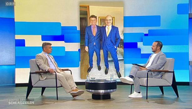 Zwei Männer im Talkshow-Studio, im Hintergrund ein Foto von zwei Männern im Anzug.