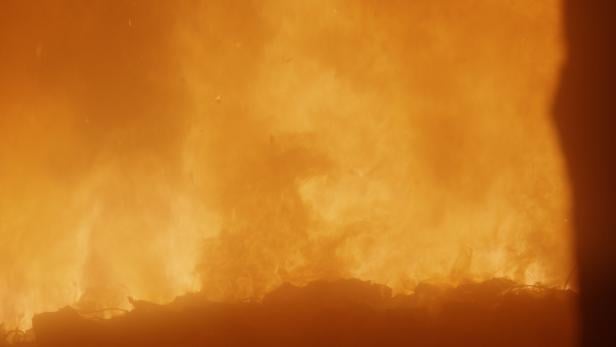 Helles, orangefarbenes Feuer lodert über dunklem Untergrund.