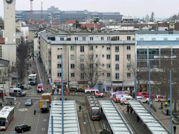 Mehrere Einsatzfahrzeuge von Polizei und Rettungskräften stehen an einer Straßenbahnhaltestelle in einer Stadt.