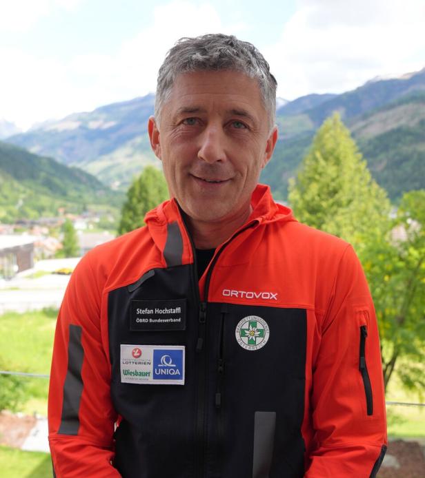 Stefan Hochstaffl vom ÖBRD Bundesverband trägt eine rote Jacke vor einer Bergkulisse.