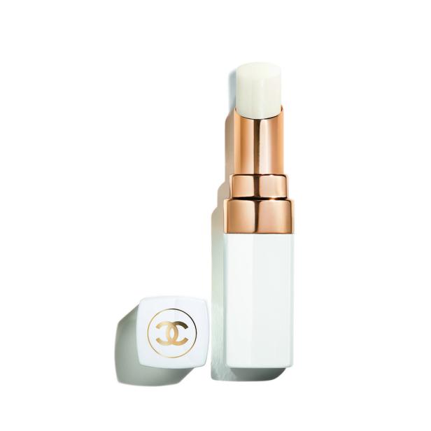 Ein Chanel Lippenpflegestift mit goldener Hülse und weißem Gehäuse steht neben seinem Deckel.