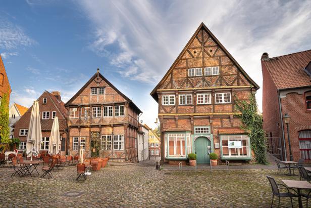 Historische Fachwerkhäuser und ein gepflasterter Platz mit Außengastronomie in der Altstadt von Mölln bei sonnigem Wetter.