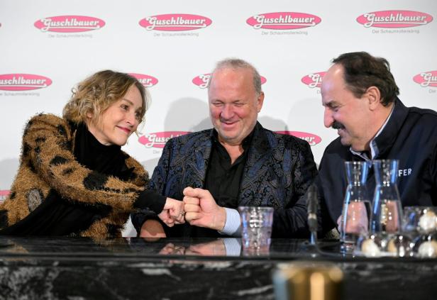 Drei Personen sitzen an einem Tisch, lächeln und geben sich freundschaftlich die Faust.