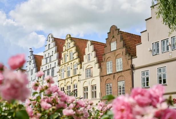 Historische Treppengiebelhäuser in Friedrichstadt mit blühenden Rosen im Vordergrund, typisch für das „Venedig des Nordens“.